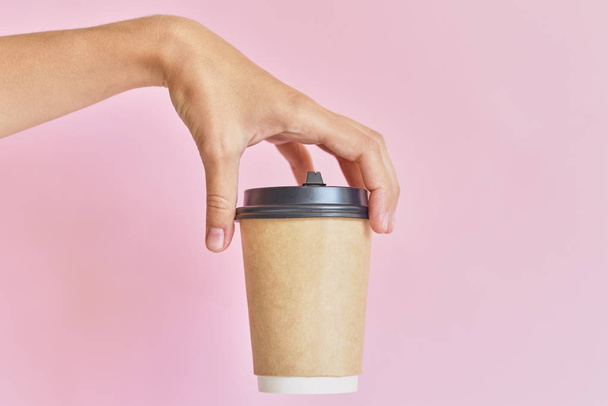 Mockup of female hand holding coffee paper cup on pink backgroun - Foto, Bild