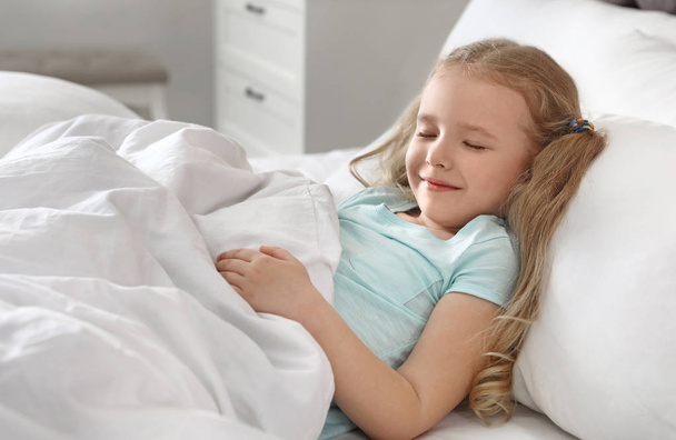 Portrait of cute little girl sleeping in large bed - Photo, Image