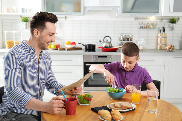 Dad and son having breakfast together in kitchen - Foto, afbeelding