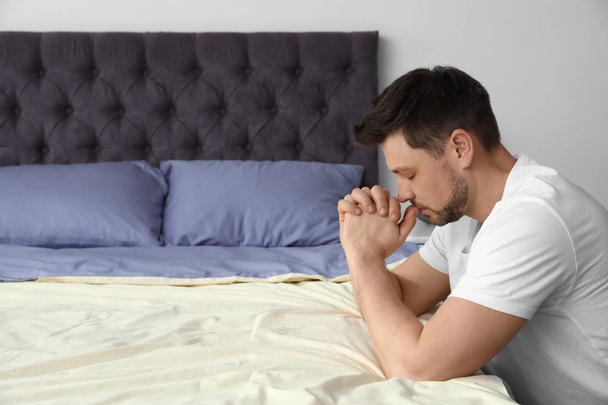 Handsome man saying bedtime prayer at home. Space for text - Φωτογραφία, εικόνα