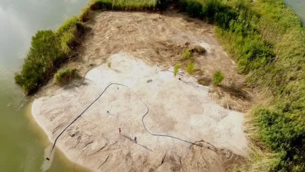 Vue aérienne par drone de la pompe de dragage sur mesure lavant le sable et approfondissant le chenal sur la côte sablonneuse de l'île de limon sur la rive d'une rivière ou d'un lac
 - Séquence, vidéo