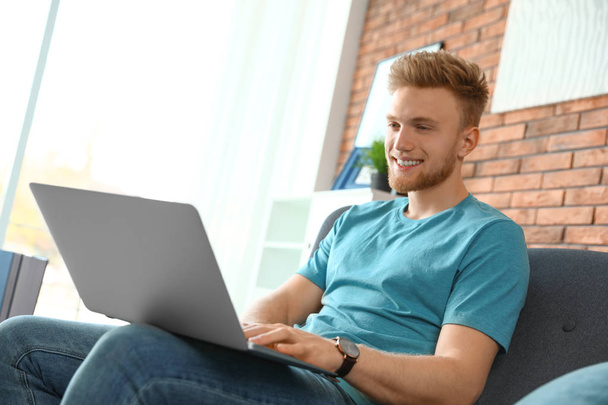 Young man using laptop in living room - Foto, Imagen