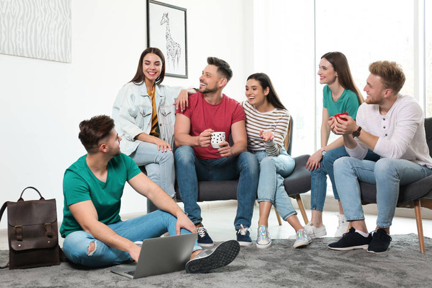 Group of happy people with laptop in living room - Fotó, kép