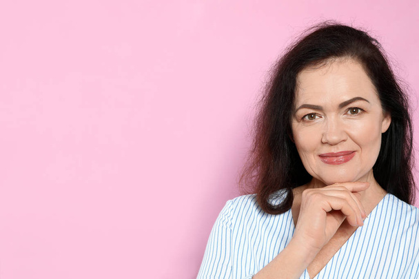 Portrait of mature woman with beautiful face on pink background. Space for text - Fotografie, Obrázek