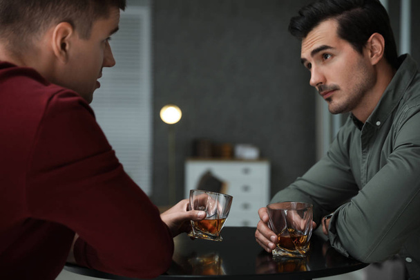 Young men drinking whiskey together in bar - Fotó, kép