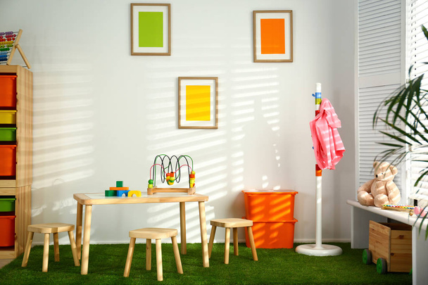 Stylish playroom interior with wooden table and stools - Фото, зображення