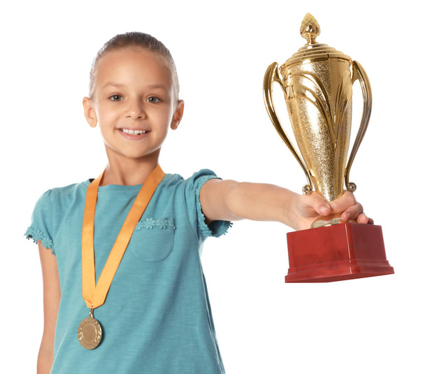 白い背景に金の勝利カップとメダルを持つ幸せな女の子 - 写真・画像