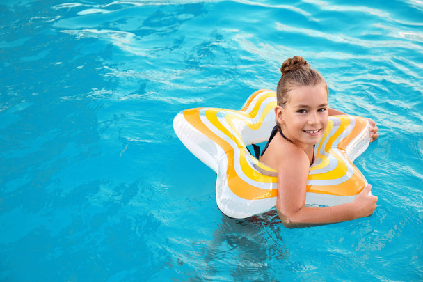 Happy little girl with inflatable ring in swimming pool - Foto, immagini