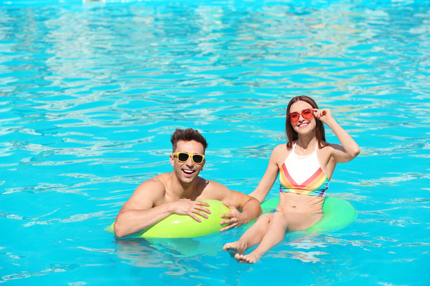 Happy young couple with inflatable rings in swimming pool - Valokuva, kuva