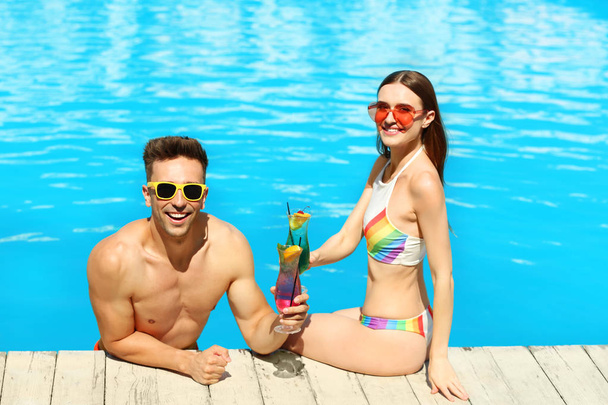Happy young couple with cocktails resting at swimming pool - Fotografie, Obrázek