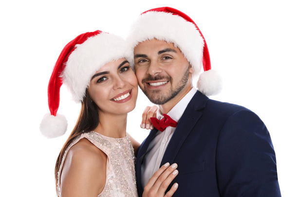 Lovely young couple in Santa hats on white background. Christmas celebration - Photo, Image