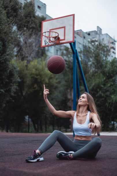 Girl on a basketball court with a ball. Sportswear dressed in leggings and top. - Foto, Imagen