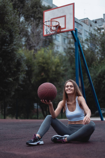 Girl on a basketball court with a ball. Sportswear dressed in leggings and top. - Fotografie, Obrázek