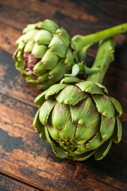 Fresh raw organically grown artichoke flower buds on wooden table - Photo, Image