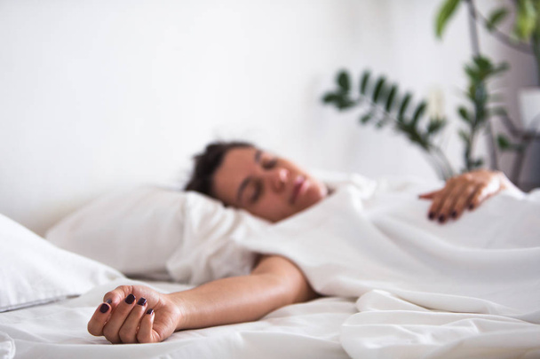 γυναίκα που κοιμάται στο κρεβάτι χέρι κοντά στην επιλεκτική εστίαση - Φωτογραφία, εικόνα