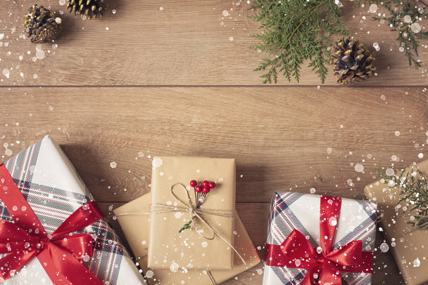 Christmas Background. Top View Of Christmas Boxes In Craft And Red Stripe Paper Decorated With Branch, Linen Cord, Red Bow On Wooden Table. Drawn Snow. Copy Space - Fotografie, Obrázek