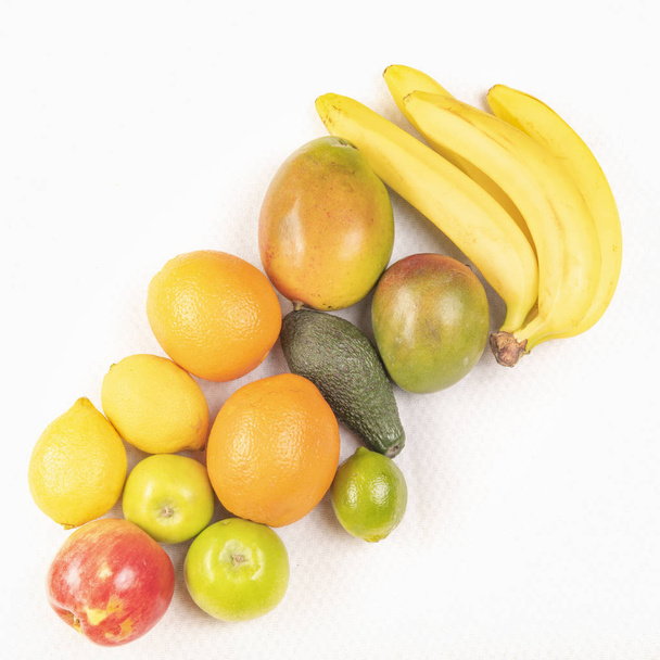 Bananas and mangos and apples and oranges and avocado on the white background - Foto, afbeelding