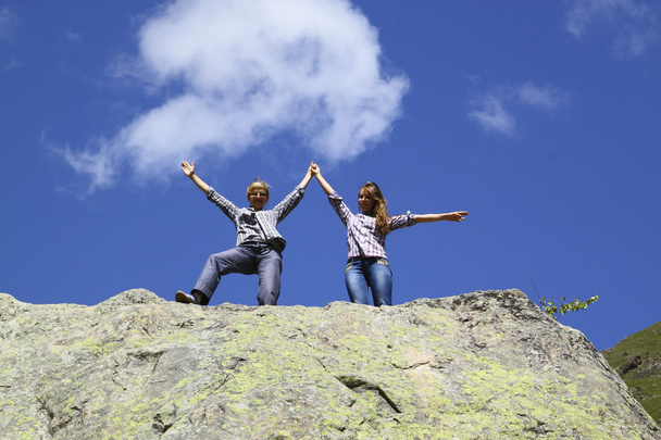 Щаслива мати і дочка стоять на величезній скелі, піднімаючи руки вгору
 - Фото, зображення