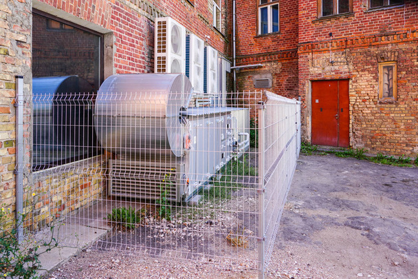 ilmastointi- ja ilmastointilaitteet vanhan tiilitalon ulkopuolella
 - Valokuva, kuva