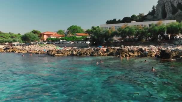 Palermo, SICILY, Italy - August 2019: Cinematic Span over a rocky stone beach. Clear, crystal, turquoise water. unrecognized people are swimming in the sea. In the background is a mountain and a - Footage, Video