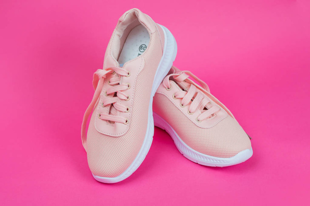 Жіноче спортивне взуття. Кросівки для бігу. Стильні модні рожеві тканинні кросівки. Жіноче спортивне взуття на рожевому тлі
. - Фото, зображення