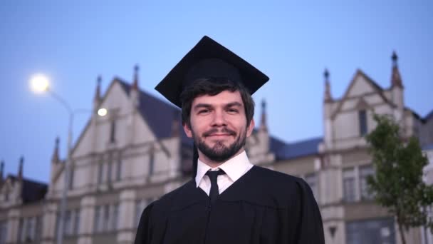 Vonzó mosolygós férfi diplomás állva és a kamerába nézve. - Felvétel, videó