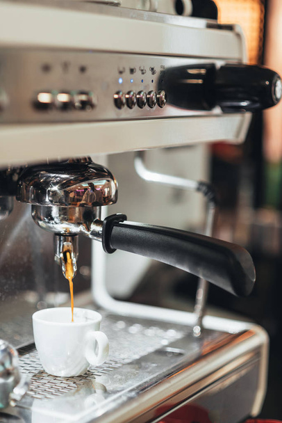 Close-up of espresso pouring from coffee machine. Professional coffee brewing. - Fotó, kép