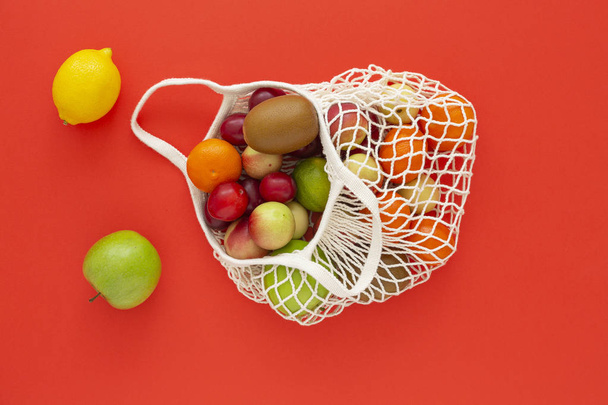 Mesh bag with fresh organic fruits on a colored background. Zero waste concept, Eco friendly or plastic free lifestyle. Top view - 写真・画像