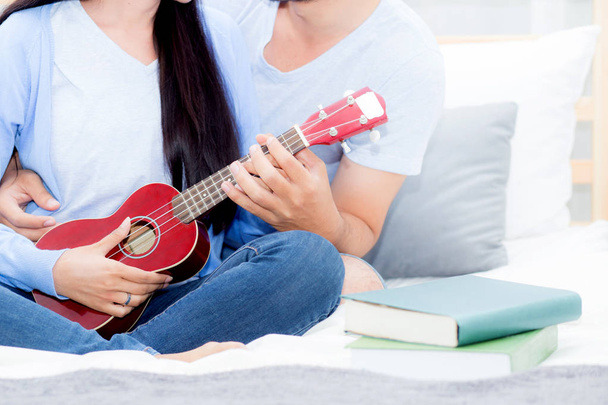 Young Asian couple playing ukulele relaxing with happiness and j - Photo, Image