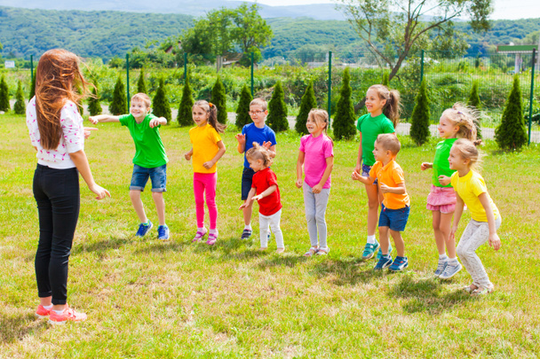 Dzieci z nauczycielem bawić się na zielonym trawniku - Zdjęcie, obraz