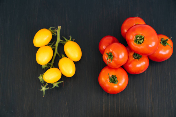 Top view of yellow and red cherry tomatoes in bowl on black wooden background - Фото, зображення