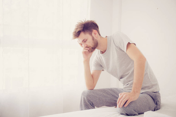 American man yawning. Man sitting a bed is serious and problem c - Photo, Image