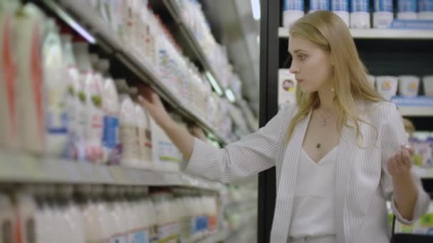 食料品店で新鮮な有機乳製品を選択し、購入する女性. - 映像、動画