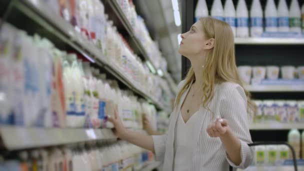 Frau wählt und kauft frische Bio-Milchprodukte im Lebensmittelgeschäft. - Filmmaterial, Video