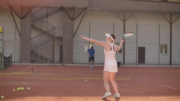 Tenis kortundaki kadın tenisçi raketle ve gün batımında yavaş çekimde tenis oynuyor - Video, Çekim