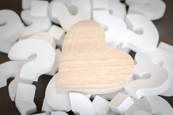 Corazón de madera sobre grupo de blanco signo de interrogación, concepto de problema
 - Foto, imagen
