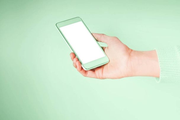 Hand with mobile phone on mint green color 2020 - Photo, Image