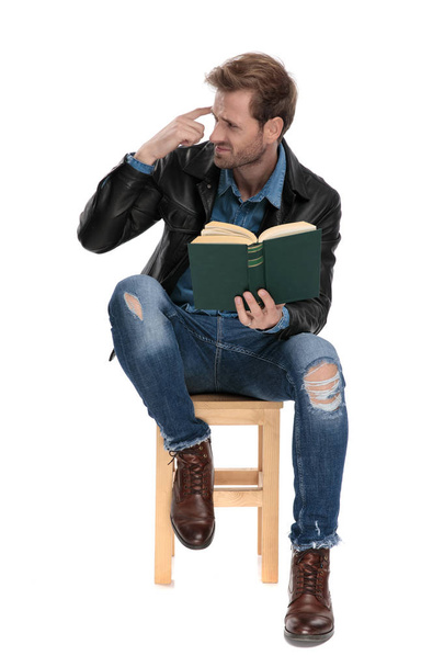 sitzender Mann mit Buch imitiert verrückte Geste - Foto, Bild