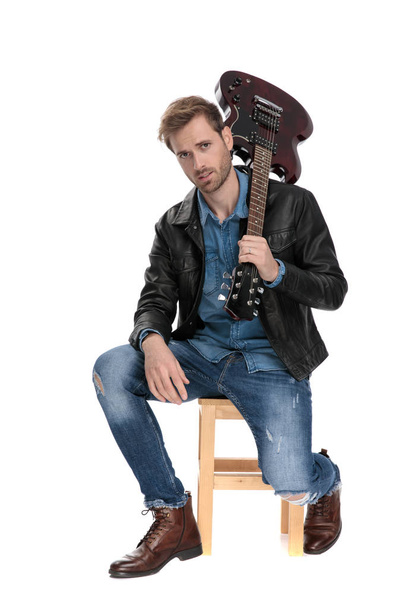siedzący mężczyzna trzyma gitarę na plecach - Zdjęcie, obraz