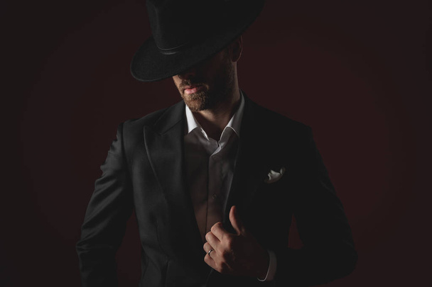 attractive man wearing tuxedo and hat fixing collar - Valokuva, kuva
