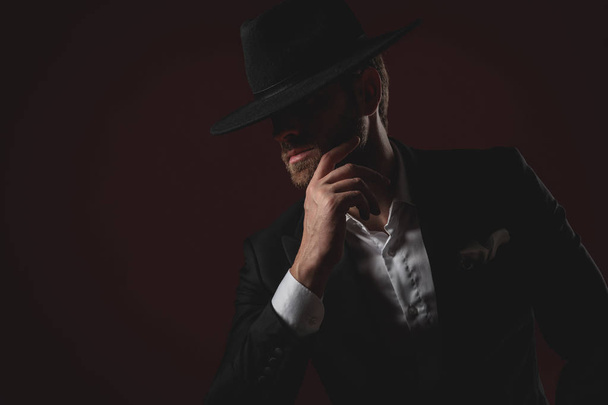 aantrekkelijke jonge man dragen Tuxedo en zwarte hoed - Foto, afbeelding
