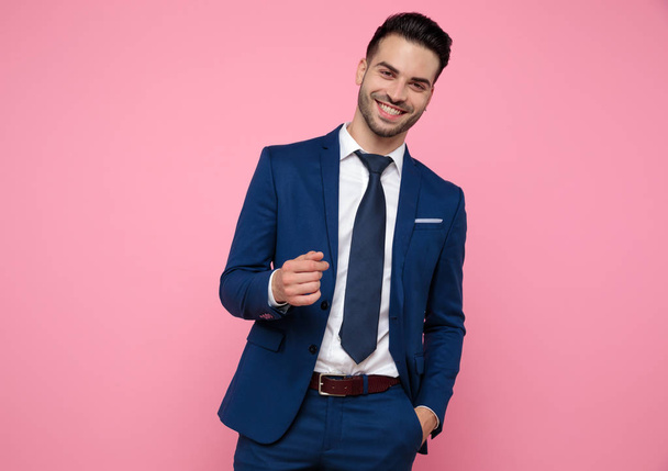 attractive young man wearing blue navy suit on pink background - Valokuva, kuva