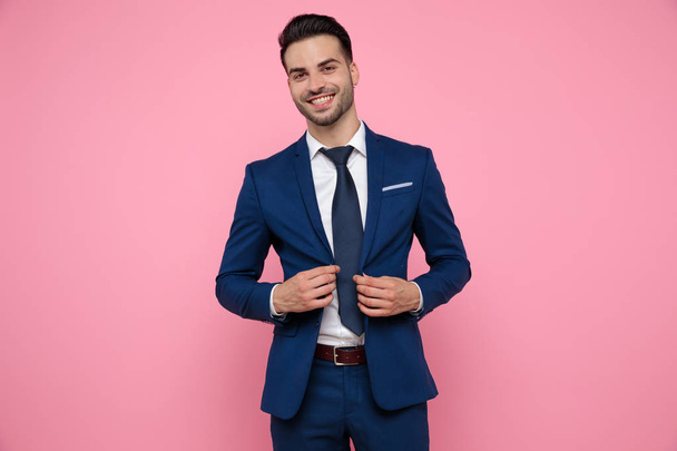attractive young man wearing blue navy suit on pink background - Foto, imagen