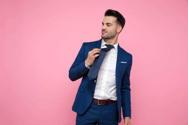 Smart Casual man Holding stropdas op roze achtergrond - Foto, afbeelding
