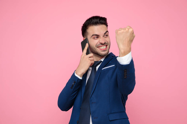 smart casual man celebrating victory on pink background - Photo, Image