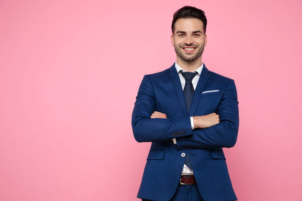 attractive young man crossing arms on pink background - Fotó, kép