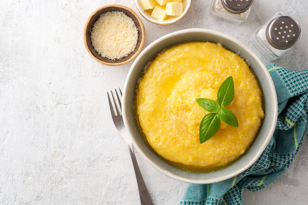 Polenta with butter and parmesan cheese in bowl on concrete background. Top view. Copy space. - Photo, Image