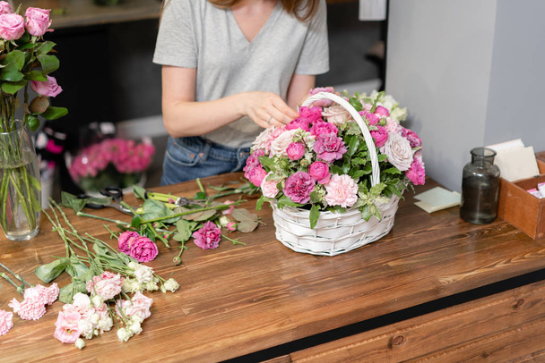 新鮮な花束を。花の配達だ。女性花屋はウィッカーバスケットに花の配置を作成します。混合花の美しい花束。花屋のコンセプト . - 写真・画像