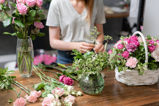 Handsome fresh bouquet. Flowers delivery. Woman florist create flower arrangement in a wicker basket. Beautiful bouquet of mixed flowers. Floral shop concept . - Foto, afbeelding