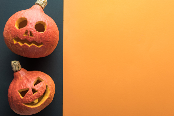 top view of carved Halloween pumpkins on orange and black background - Photo, Image